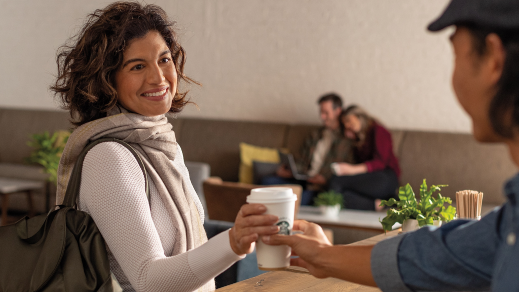 Woman smiling while being handed a cup of Starbucks coffee