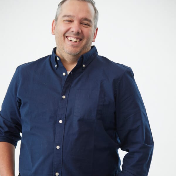 Professional headshot of a cheerful person in a navy blue shirt smiling confidently