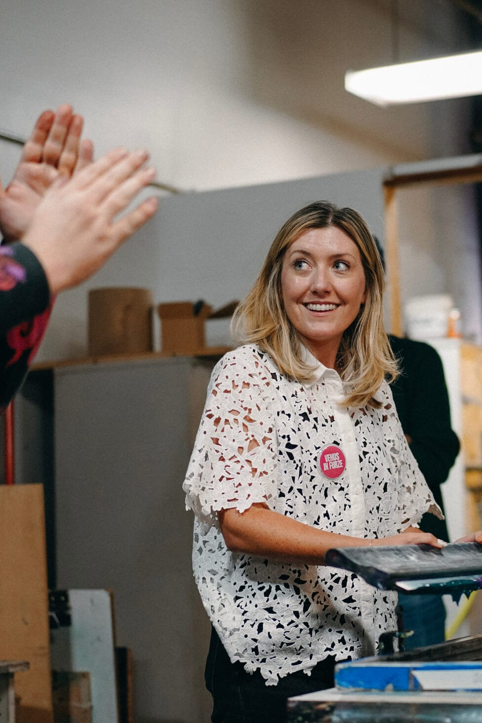 Enthusiastic reaction from a workshop participant with another person's hand raised in foreground