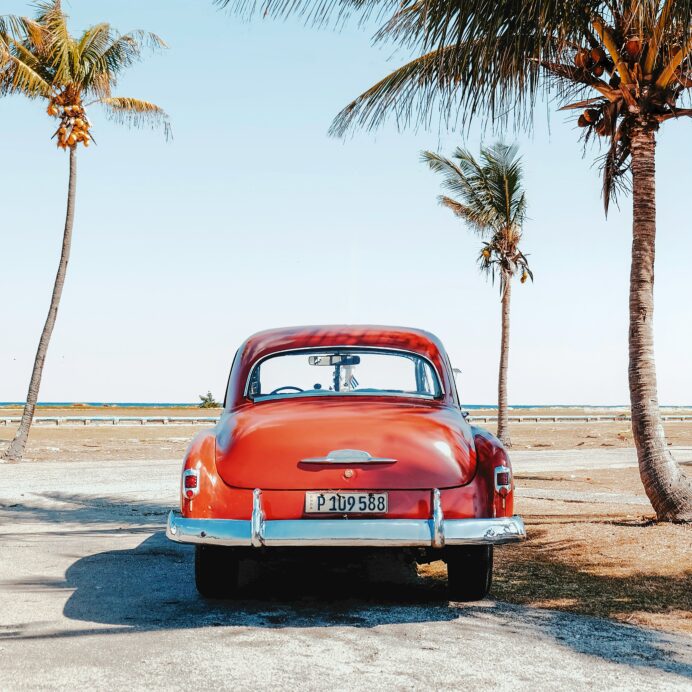 Vintage red car parked with palm trees surrounding