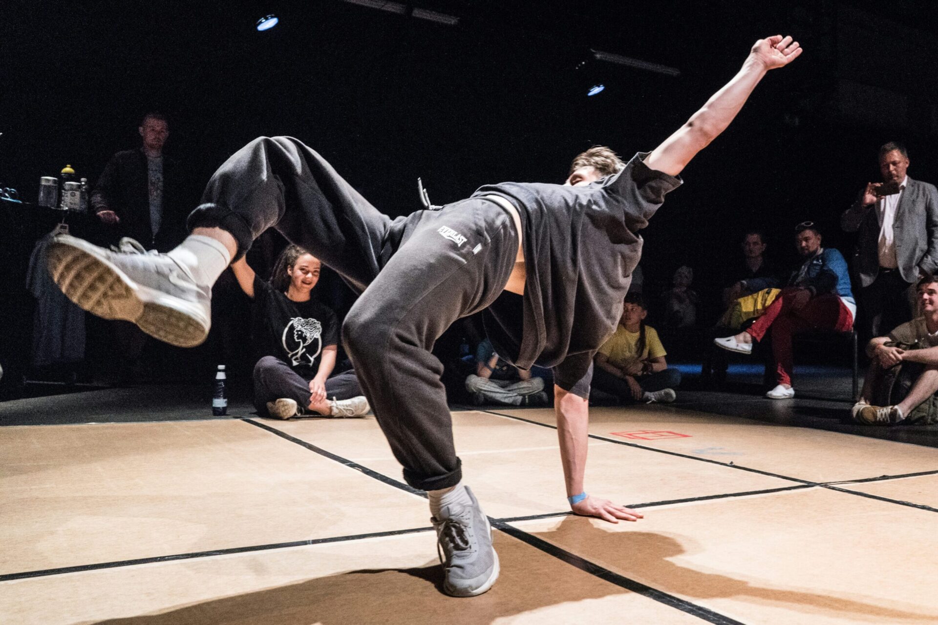 Man breakdancing in front of a darkened crowd