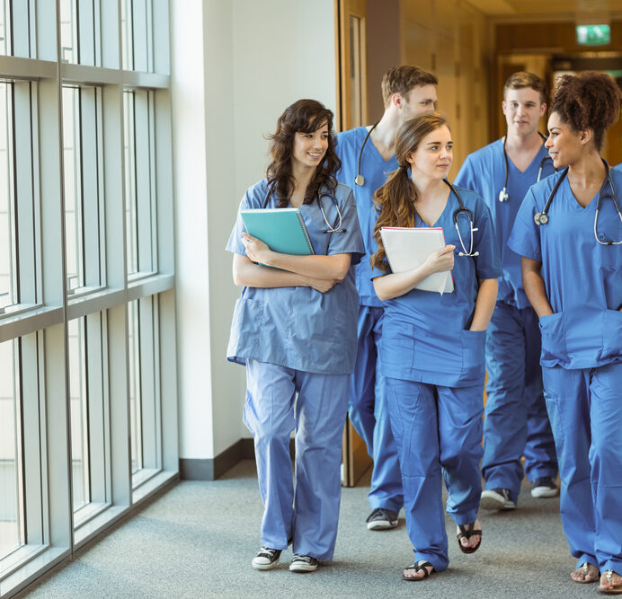 Team of medical professionals walking down hallway in scrubs