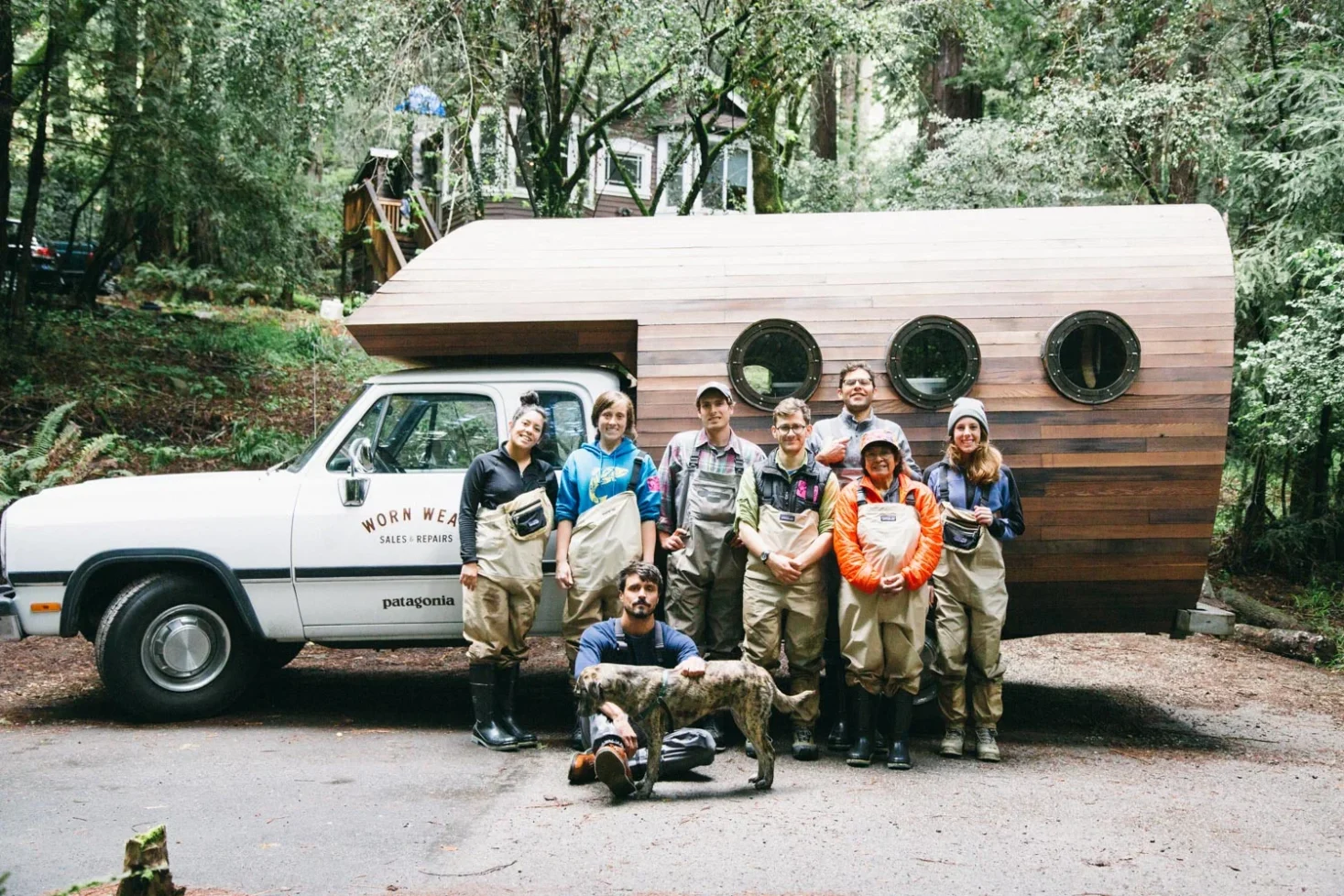 Team of people in outdoor workwear smiling in front of a Worn Wear Patagonia truck