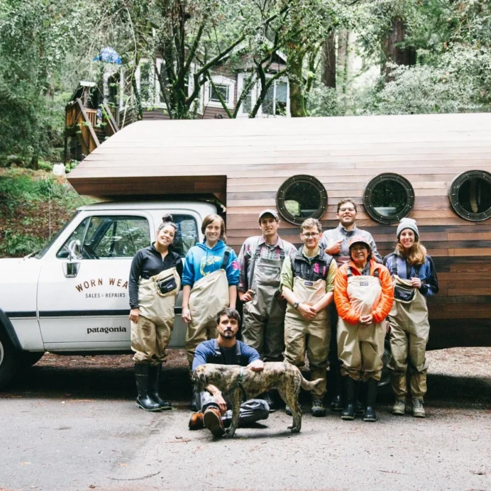 Team of people in outdoor workwear smiling in front of a Worn Wear Patagonia truck