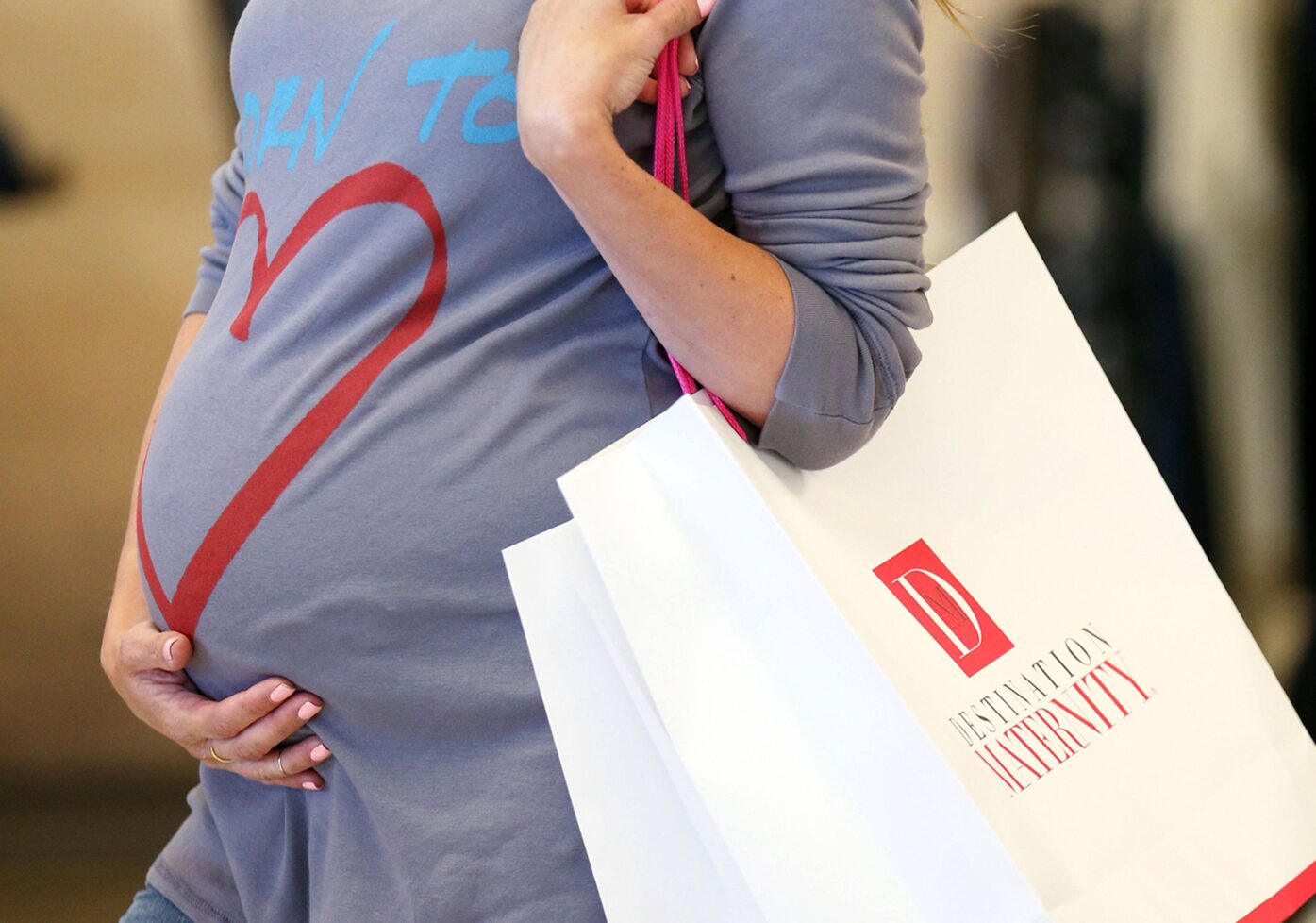 Woman holding pregnant stomach holding a bag with the text Destination Maternity