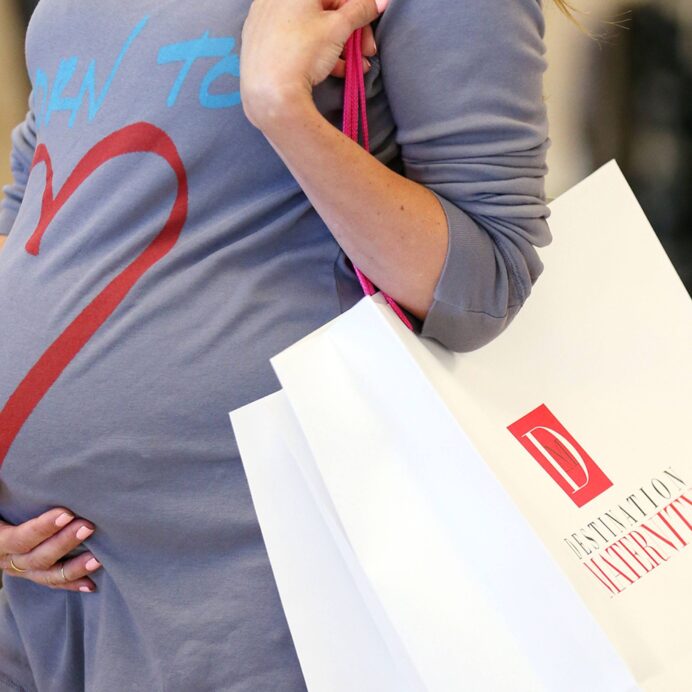 Woman holding pregnant stomach holding a bag with the text Destination Maternity