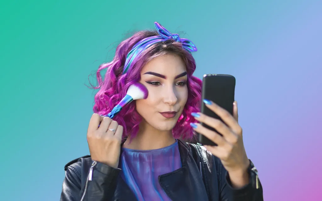 A woman applying makeup and using a phone as a mirror