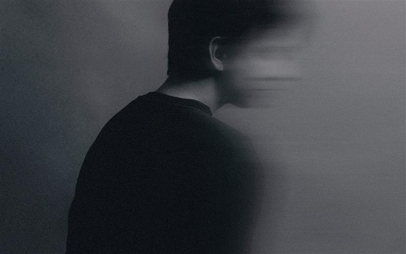 Black and white editorial style photograph of white man from behind with his head turning away from the camera, blurry.