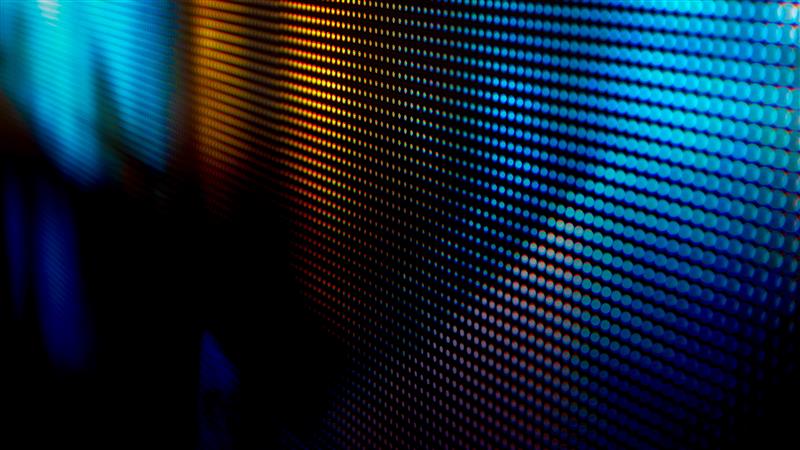 A series of rows and columns of dots in a golden yellow hue on the left that gradually fades into a blue hue on the right against a black background