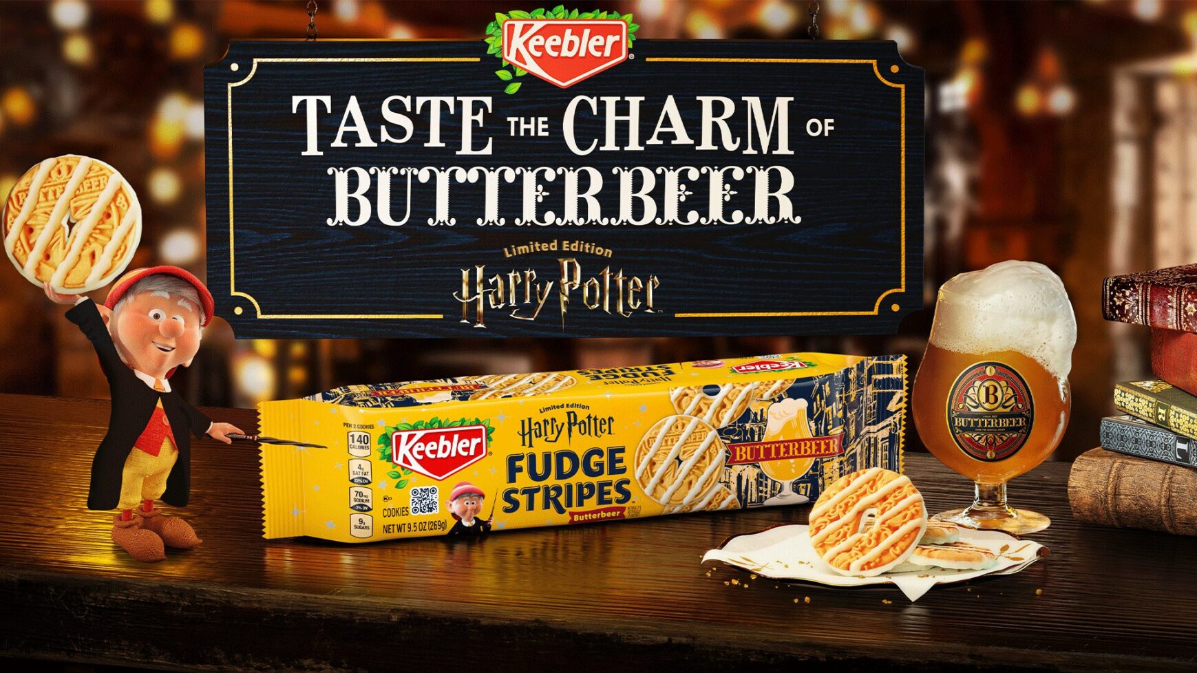 Key visual of a dark toned wood tabletop with a package of Fudge Stripe cookies and Ernie the Elf next to a glass of Harry Potter Butterbeer